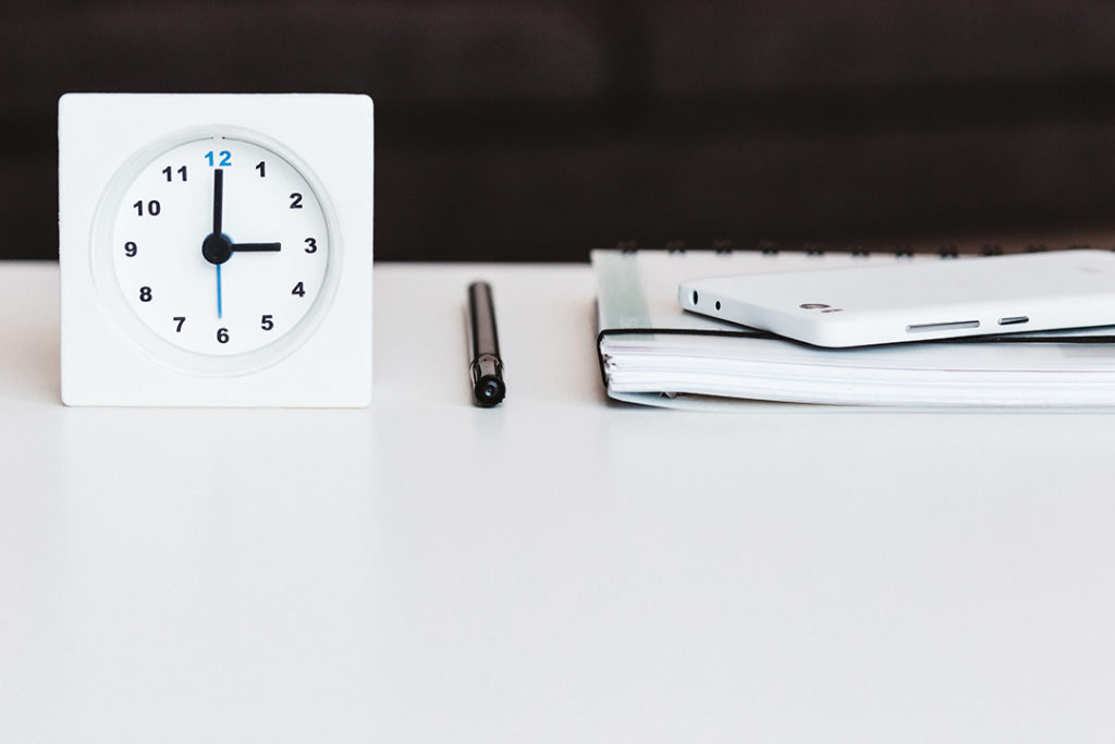 Ticking Clock on Desk with Phone, Pen and Notepad for Insurance