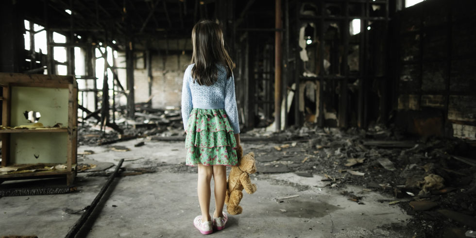 Girl Looks at House after Fire While Holding Teddy Bear