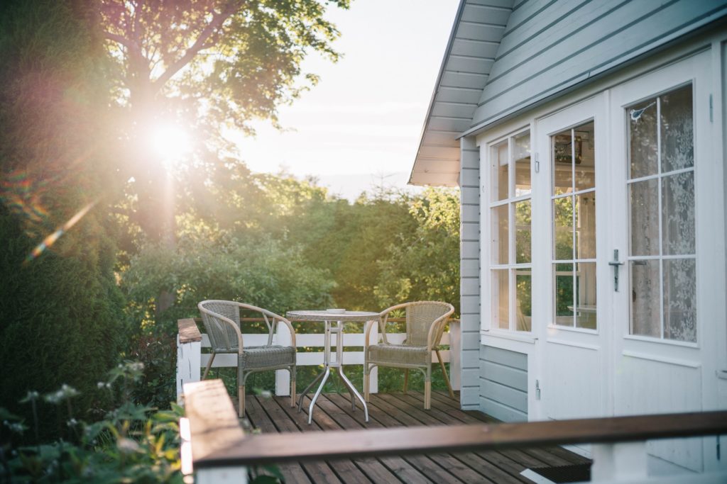 The Back Porch of an Insured House in the Woods with Sunlight Shining Through the Trees