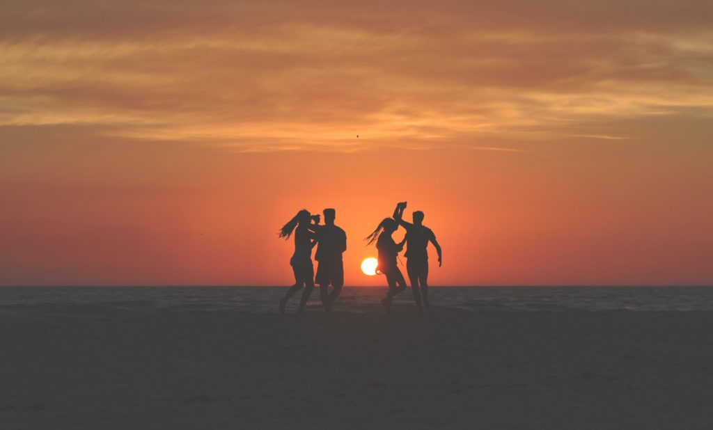 four people on the beach at sunset