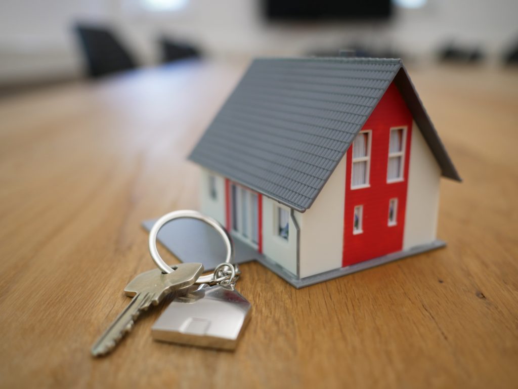 Mini house with keychain and key next to it 